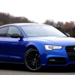 Elegant blue luxury car parked outdoors against a natural backdrop.